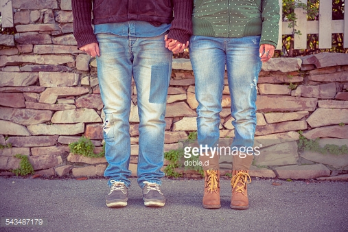 Love couple legs holding hands over stone wall